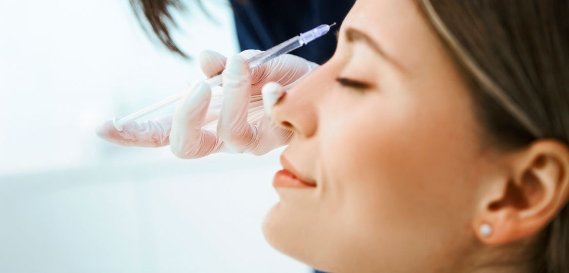 Junge Frau bekommt Botox in die Stirn mit einer Spritze injiziert